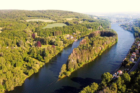 Vista aerea di una sistemazione glamping su un fiume circondato da alberi e case nelle vicinanze.