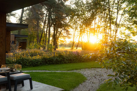 Zonnig tuinzicht met terras aan Holiday villa Boslodge 2 met sauna en hondenafrastering bij Hofparken Wiltershaar.