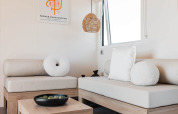 Modern glamping accommodation with light wooden furniture, cozy white cushions, and minimalist decor.