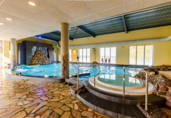 Area piscina coperta in una sistemazione glamping con vasca idromassaggio e grandi finestre luminose.
