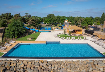 Piscina esterna con lettini, scivoli d'acqua e area giochi in una struttura glamping immersa nel verde.