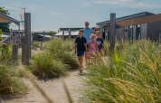 Una familia camina entre dunas en el Dune Lodge de EuroParcs Parc du Soleil en los Países Bajos en un día soleado.