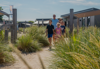 Una familia camina entre dunas en el Dune Lodge de EuroParcs Parc du Soleil en los Países Bajos en un día soleado.