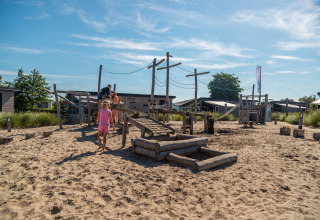 Niños juegan en un parque infantil de arena en Dune Lodge, EuroParcs Parc du Soleil, Países Bajos, día soleado.