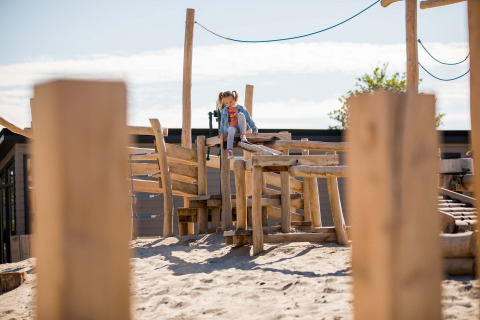 Enfant jouant sur une structure en bois dans le sable à Dune Lodge, EuroParcs Parc du Soleil, Pays-Bas