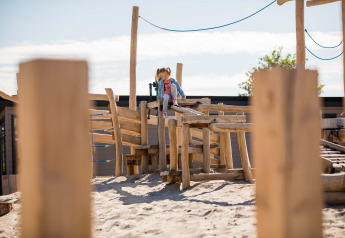 Kind speelt op een houten klimtoestel in het zand bij Dune Lodge, EuroParcs Parc du Soleil, Nederland
