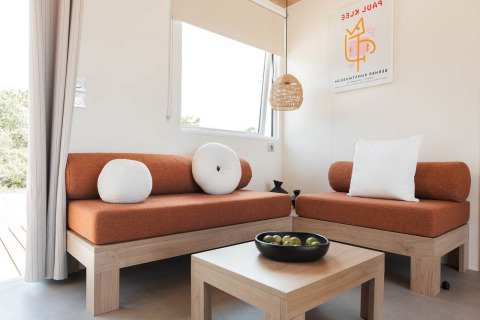 Moderne woonkamer in Sunset Lodge, Vakantiepark Leukermeer, Nederland met oranje zetels en houten meubels.