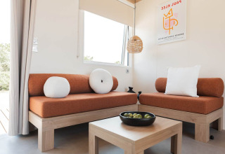 Moderne woonkamer in Sunset Lodge, Vakantiepark Leukermeer, Nederland met oranje zetels en houten meubels.