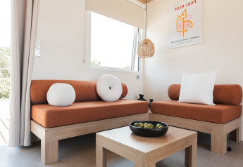 Salón moderno en Sunset Lodge, Vakantiepark Leukermeer, Países Bajos, con sofás naranjas y decoración de madera.