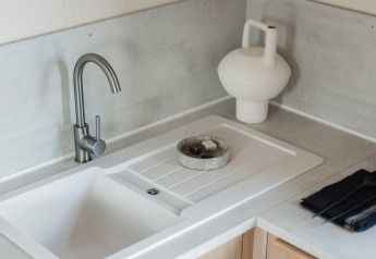 Moderne Spüle mit Wasserhahn in einer Glamping-Unterkunft; minimalistische Arbeitsplatte und Deko.