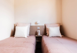 Twee eenpersoonsbedden met roze beddengoed en witte kussens bij Sunset Lodge, knusse sfeer.