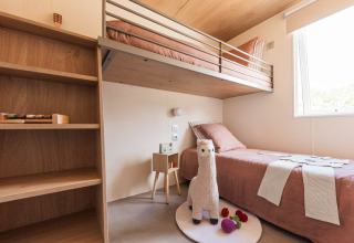 Moderne lodgekamer in Sunset Lodge, Vakantiepark Leukermeer met stapelbed, raam en speellama.