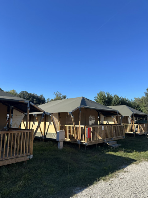 Safari-telte kaldet Cottage på Vigna sul Mar Family Camping Village i Italien under en klar blå himmel.