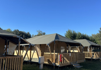 Safari tents named Cottage at Vigna sul Mar Family Camping Village in Italy under a clear blue sky.