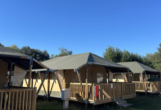 Tiendas safari llamadas Cottage en Vigna sul Mar Family Camping Village en Italia bajo un cielo azul claro.