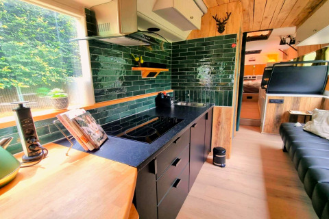 Moderne mobilhome keuken met groene tegels en zithoek in REEBUS, op locatie in België.