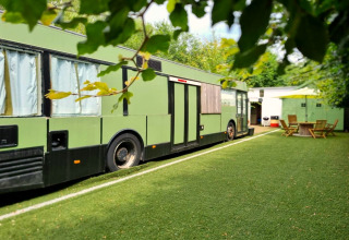 Mobiel huis REEBUS geparkeerd op kunstgras in België met tuinmeubilair op de achtergrond.