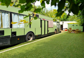 Mobiele woning genaamd REEBUS geparkeerd op kunstgras in België met tuinmeubilair op de achtergrond.
