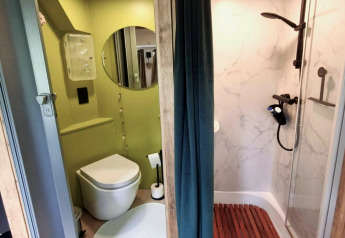 Moderne badkamer in REEBUS mobilhome in België met douche, toilet, ronde spiegel en gordijn als scheiding.