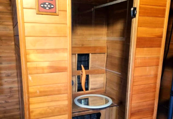 Binnenfoto van een houten sauna met een rond raam, genomen in het mobiele huis 'REEBUS' in België.