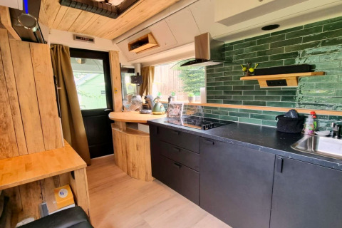 Modern mobilhome keukeninterieur met groene tegels en houtaccenten in REEBUS, België.