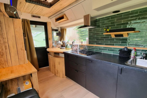 Moderne mobilhome-køkken interiør med grøn flisevæg og træelementer i REEBUS, Belgien.