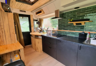 Moderne mobilhome-køkken interiør med grøn flisevæg og træelementer i REEBUS, Belgien.