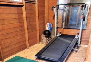 Fitnessruimte in een mobiel huis met loopband, houten wanden en grote spiegel, foto genomen in België.