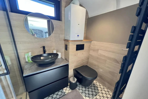 Baño moderno en Pine Tree Tiny Cottage, Bélgica, con lavabo y váter negros, decoración elegante y azulejos geométricos.