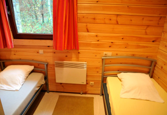 Gemütliches Schlafzimmer mit zwei Einzelbetten, Holzverkleidung und Fenster im Chalet De Boshut, Belgien.