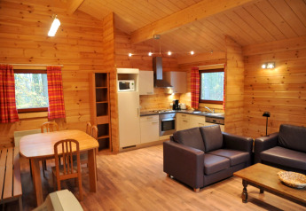 Innenansicht eines Chalets 'De Boshut' in Belgien mit Küche, Essbereich und gemütlichem Wohnzimmer.