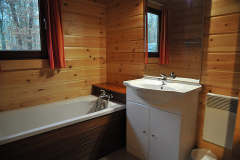 Salle de bain en bois avec baignoire, lavabo et fenêtres dans le chalet « De Boshut » en Belgique.