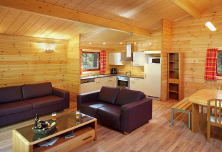 Cozy living room and kitchen inside the chalet «De Boshut» in Belgium, featuring wood decor and modern furnishings.
