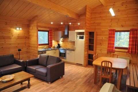Intérieur d’un chalet en bois chaleureux nommé « De Boshut » en Belgique avec cuisine, salon et salle à manger.