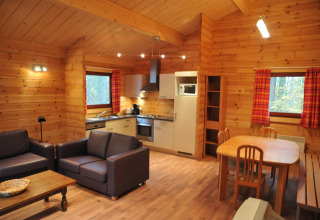 Intérieur d’un chalet en bois chaleureux nommé « De Boshut » en Belgique avec cuisine, salon et salle à manger.