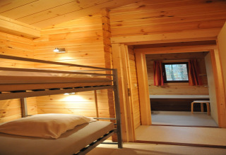Photo intérieure d'un chalet en bois à De Boshut, Belgique, avec des lits superposés et une fenêtre.
