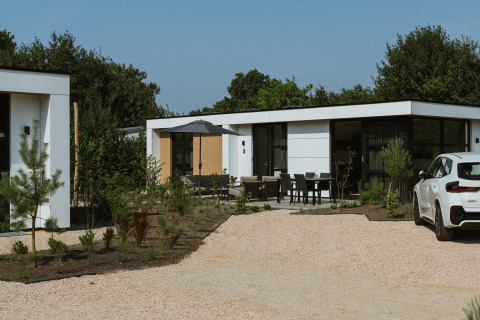 Moderne lodge Villa Bloomingdale Wellness met buitenterras, tuinmeubilair en een witte auto op de oprit.