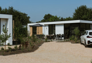 Moderne lodge Villa Bloomingdale Wellness met buitenterras, tuinmeubilair en een witte auto op de oprit.