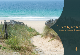 Pad door grasduinen met houten hekken naar het strand en de zee bij een glamping accommodatie.
