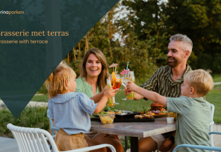 Een gezin geniet van eten en drinken op het terras van een glamping-brasserie, omgeven door natuur.