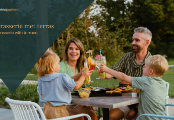 Eine Familie genießt Speisen und Getränke auf der Terrasse eines Glamping-Brasseries im Grünen.