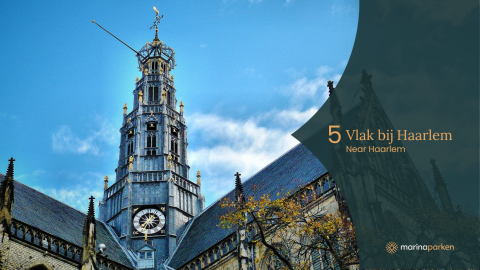 Uitzicht op een iconische toren vlak bij Haarlem, Nederland, met blauwe lucht, bomen en historische architectuur.