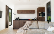 Moderne lodge met gezellige beige bank, compacte keuken in hout, grote ramen en veel daglicht.