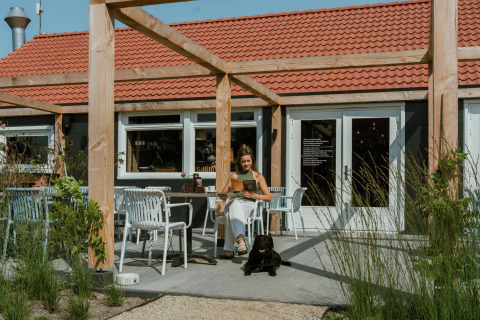 Vrouw met zwarte hond zit buiten bij Villa Bloomingdale, MarinaPark Residentie Bloemendaal in Nederland.