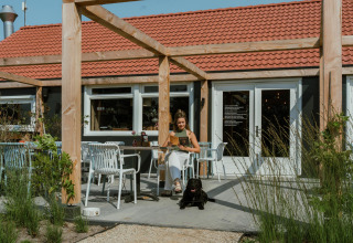 Vrouw met zwarte hond zit buiten bij Villa Bloomingdale, MarinaPark Residentie Bloemendaal in Nederland.
