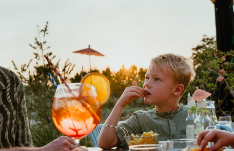 Een jongen eet friet bij zonsondergang op het terras van Villa 'Bloomingdale' in MarinaPark Residentie Bloemendaal.