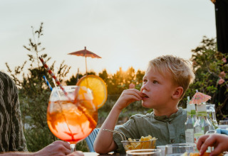 Een jongen eet friet bij zonsondergang op het terras van Villa 'Bloomingdale' in MarinaPark Residentie Bloemendaal.