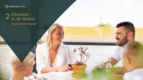 A family enjoys dinner together at a table in a modern glamping accommodation near the harbor.