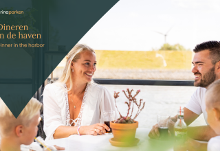 Eine Familie genießt gemeinsam ein Abendessen am Tisch in einer modernen Glamping-Unterkunft am Hafen.