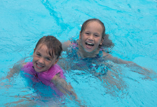 Twee lachende kinderen zwemmen samen in het zwembad van Vakantiepark 't Rheezerwold in Overijssel.